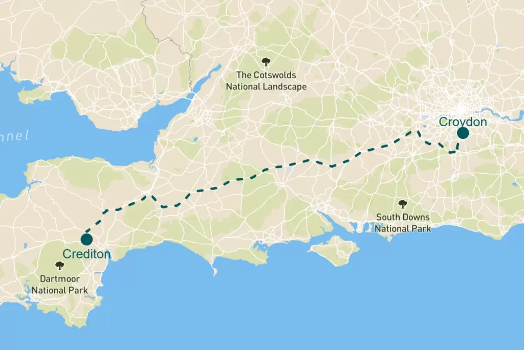 Map showing the route from Croydon to Crediton, highlighting three areas of natural beauty including the South Downs National Park, the Cotswolds National Landscape and Dartmoor National Park. A dashed line indicates the path connecting the two locations.